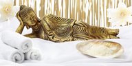 eine liegende Buddhafigur, daneben Handtücher und eine Schale