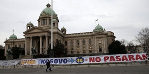 Vor einem großen Gebäude ist ein Banner aufgespannt, auf dem „Espana: Kosovo -> EU No Pasaran“ steht