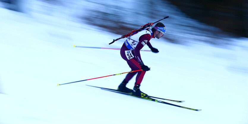 Biathlet, der auf Skiern schnell einen Berg herunterfährt