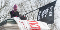 Mann mit pinker Sturmhaube schwenkt Anti-Nazi-Fahne