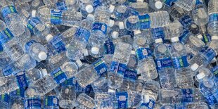 Plastikwasserflaschen mit blauen Etiketten stapeln sich übereinander