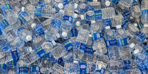 Plastikwasserflaschen mit blauen Etiketten stapeln sich übereinander