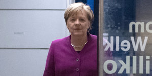 Angela Merkel lächelt und trägt ein magentafarbenes Sakko