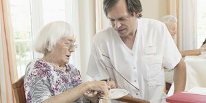 Ein Pfleger hilft einer Seniorin beim Essen
