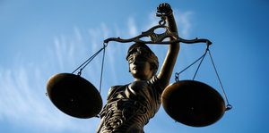 Eine Justizia-Figur vor blauem Himmel