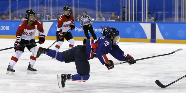 Eine Eishockey-Spielerin hechtet einem Puck hinterher