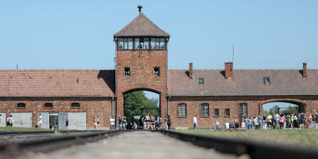 Besucher gehen vor dem historischen Tor durch das frühere deutsche Vernichtungslager Auschwitz-Birkenau in Oswiecim