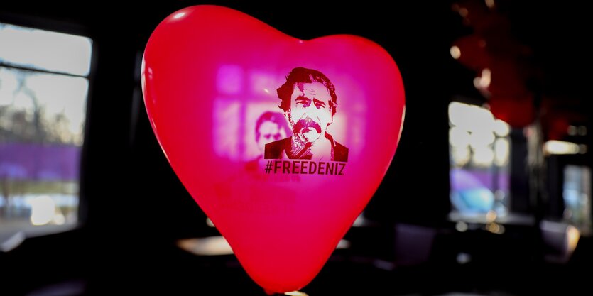 Ein roter Luftballon in Herzform mit dem Konterfei von Deniz Yücel