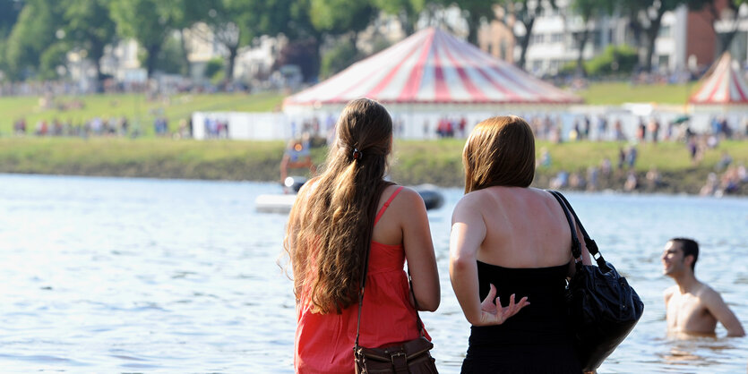 Frauen stehen bis zu den Knien im Wasser, dahinter die Breminale