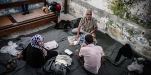 zwei Männer, eine Frau und ein Baby sitzen auf Decken auf dem Boden