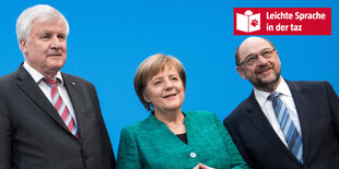 Zwei Männer und eine Frau im Anzug stehen vor einer blauen Wand