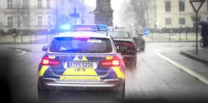 ein Polizeiauto von hinten mit Blaulicht fährt durch ein winterliches München