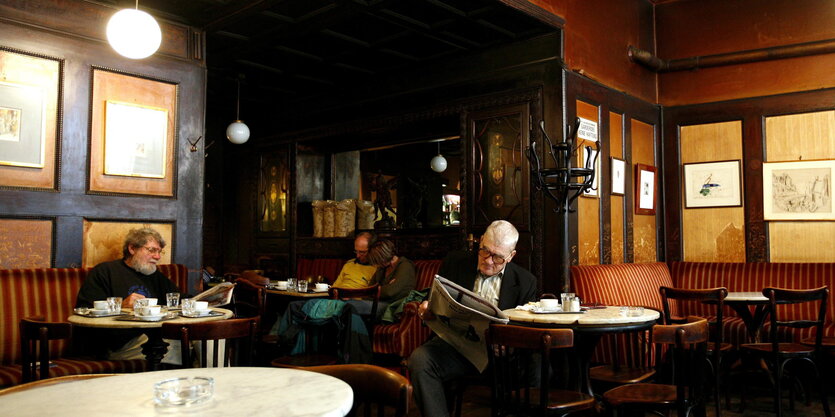 In einem Kaffeehaus sitzen Männer und lesen