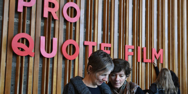 Unter dem Logo von Pro Quote Film stehen zwei Frauen und unterhalten sich