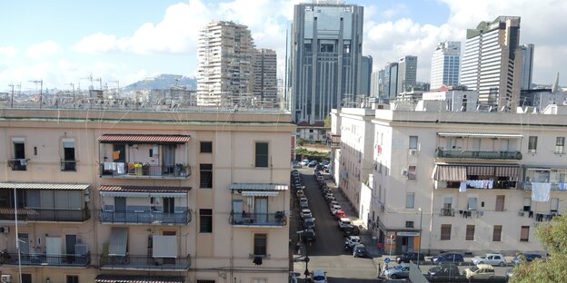 Ein Blick auf die Stadt Neapels. Im Vordergrund stehen Wohnhäuser, in Hintergrund Hochhäuser.