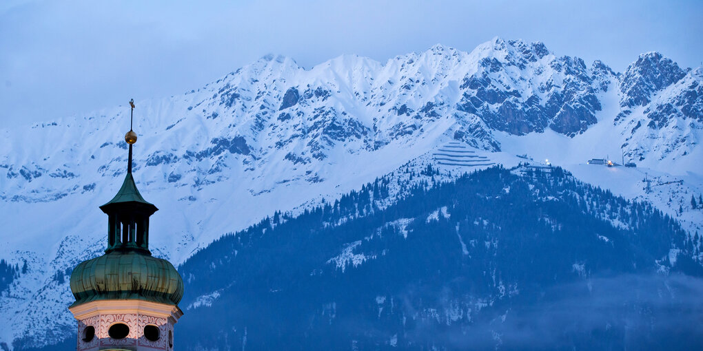 Blick auf den Turm der Spitalskirche vor der Kulisse der Nordkette in Innsbruck.