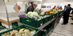 Mehrere Menschen stehen an Kisten voller Essen