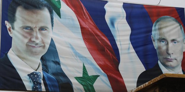 Ein Plakat mit den Gesichtern von Assad und Putin sowie der syrischen und der russischen Flagge