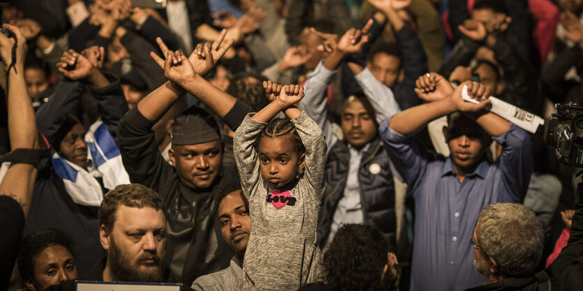 Flüchtlinge heben die Hände wie mit Handschellen gefesselt