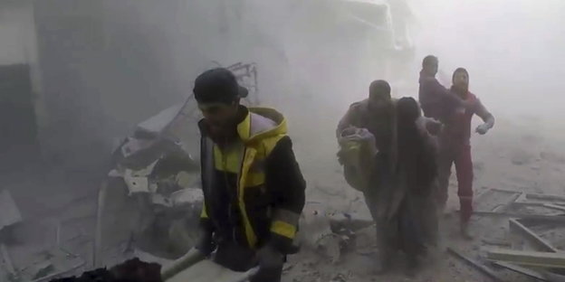 Menschen in einer staubigen und zerstörten Straße in Ost-Ghouta