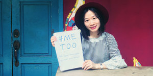 Eine junge Frau hält ein Blatt Papier hoch, auf dem "Me Too" steht