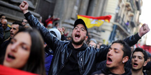 Demonstranten tragen ein rotes Banner und rufen laut