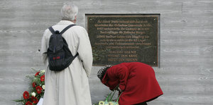 zwei Personen vor einer Gedenktafel