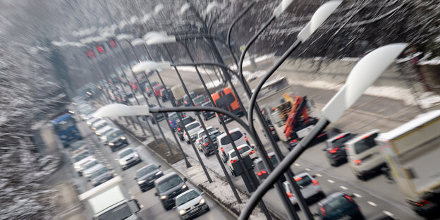 Dichter Verkehr in beide Richtungen auf dem Mittleren Ring in München, drumherum liegt Schnee