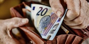Ein älterer Menschen zieht einen 20 Euro-Schein aus seiner Geldbörse