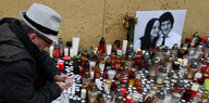 Ein Mann zündet eine Kerze am Foto Jan Kuciaks und seiner Freundin an