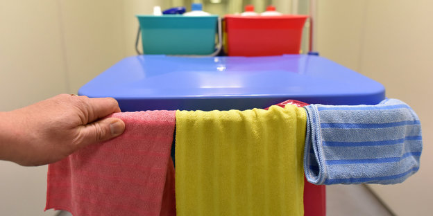 Eine Hand schiebt einen Putzwagen einen Gang entlang Eine Hand schiebt einen Putzwagen einen Gang entlang