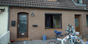 Eine Haussfassade aus braunen Ziegeln. Im Rahmen der Tür ist eine Folie gespannt.