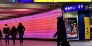 Essen: Nutzer des öffentlichen Nahverkehrs gehen durch einen pinkfarben erleuchteten Tunnel zu den Bussen und Bahnen.