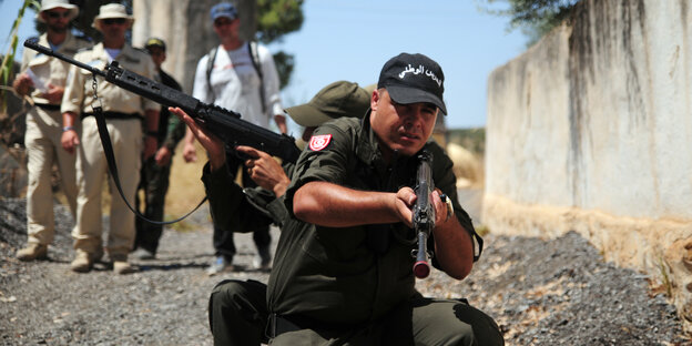 Deutsche Bundespolizisten in hellen Uniformen beobachten eine Übung der tunesischen Nationalgarde im Ausbildungszentrum Oued Zerga