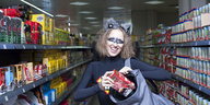 Eine Frau im Pandabär-Kostüm steht im Supermarkt und steckt eine Packung Kaffee in ihren Rucksack.