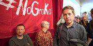 Kevin Kühnert mit einer Jacke über dem Arm, hinter ihm ein rotes Transparent mit der Aufschrift „#NoGroko“