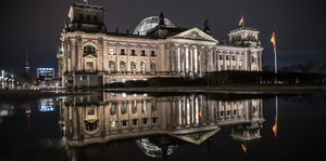 Reichstag bei Dunkelheit spiegelt sich im Wasser