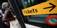 Ein Mensch steigt in einen Bus ein, neben der Tür klebt ein großer, gelber Aufkleber mit der Aufschrift „Tickets“