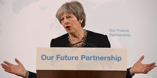 Theresa May an einem Stehpult auf dem steht „Our Future Partnership“. Ihre Hände sind links und rechts neben dem Schild zu sehen