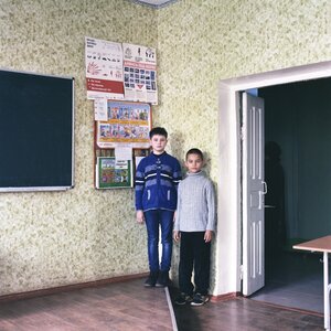Zwei Jungs stehen in der Ecke eines Klassenzimmers, hinter ihnen, an der Wand hängen bunte Plakate Zwei Jungs stehen in der Ecke eines Klassenzimmers, hinter ihnen, an der Wand hängen bunte Plakate