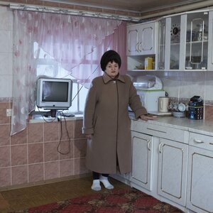 Eine Frau steht in einer Küche, sie trägt Mantel und Mütze Eine Frau steht in einer Küche, sie trägt Mantel und Mütze