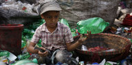 Ein kleiner Junge sitzt in einem Berg aus Plastikflaschen