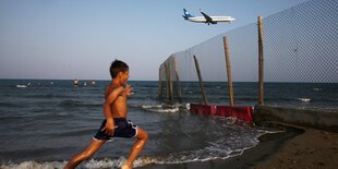 Leute am Strand, darüber ein Flugzeug