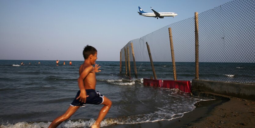 Leute am Strand, darüber ein Flugzeug