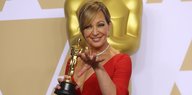 Eine Frau in einem roten Kleid mit einer Oscar-Figur in der Hand