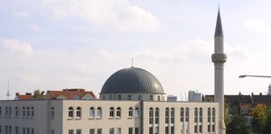 Die Kuppel einer Moschee vor blassblauem Himmel