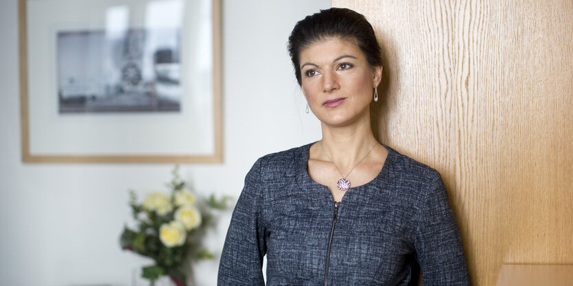 Sahra Wagenknecht lehnt sich an einen Holzschrank