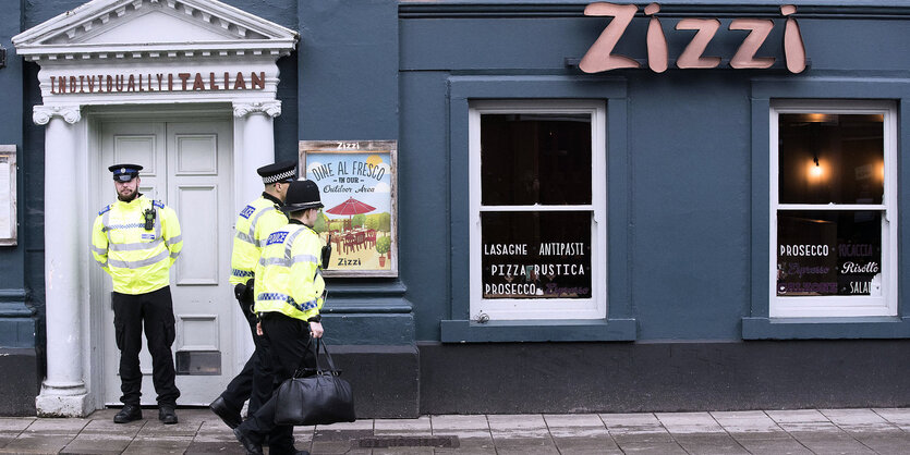 Die Front einer geschlossenen Pizzeria - davor Polizisten