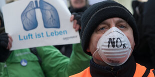 Mann mit schwarzer Mütze und weißer Atemmaske. Auf der Maske steht NOx