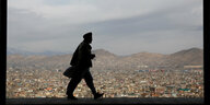Ein Mann läuft auf einer Mauer mit Bilck auf Kabul